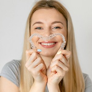 Woman holding two aligners to make a heart shape