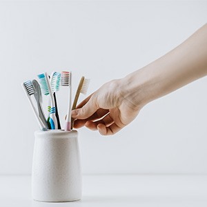 Hand about to take toothbrush out of holder