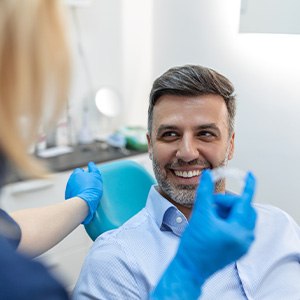 Smiling dental patient looking at dentist holding Invisalign aligner