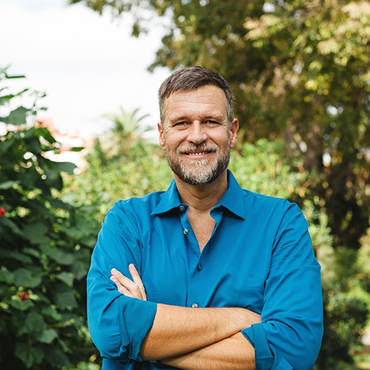 Man standing outside smiling with arms folded