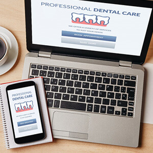 dental forms on laptop and phone on desk with supplies