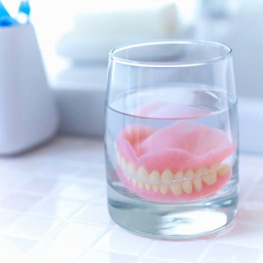 Dentures soaking in a glass