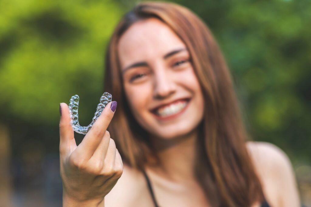 Woman blurry in background holding Invisalign in the foreground